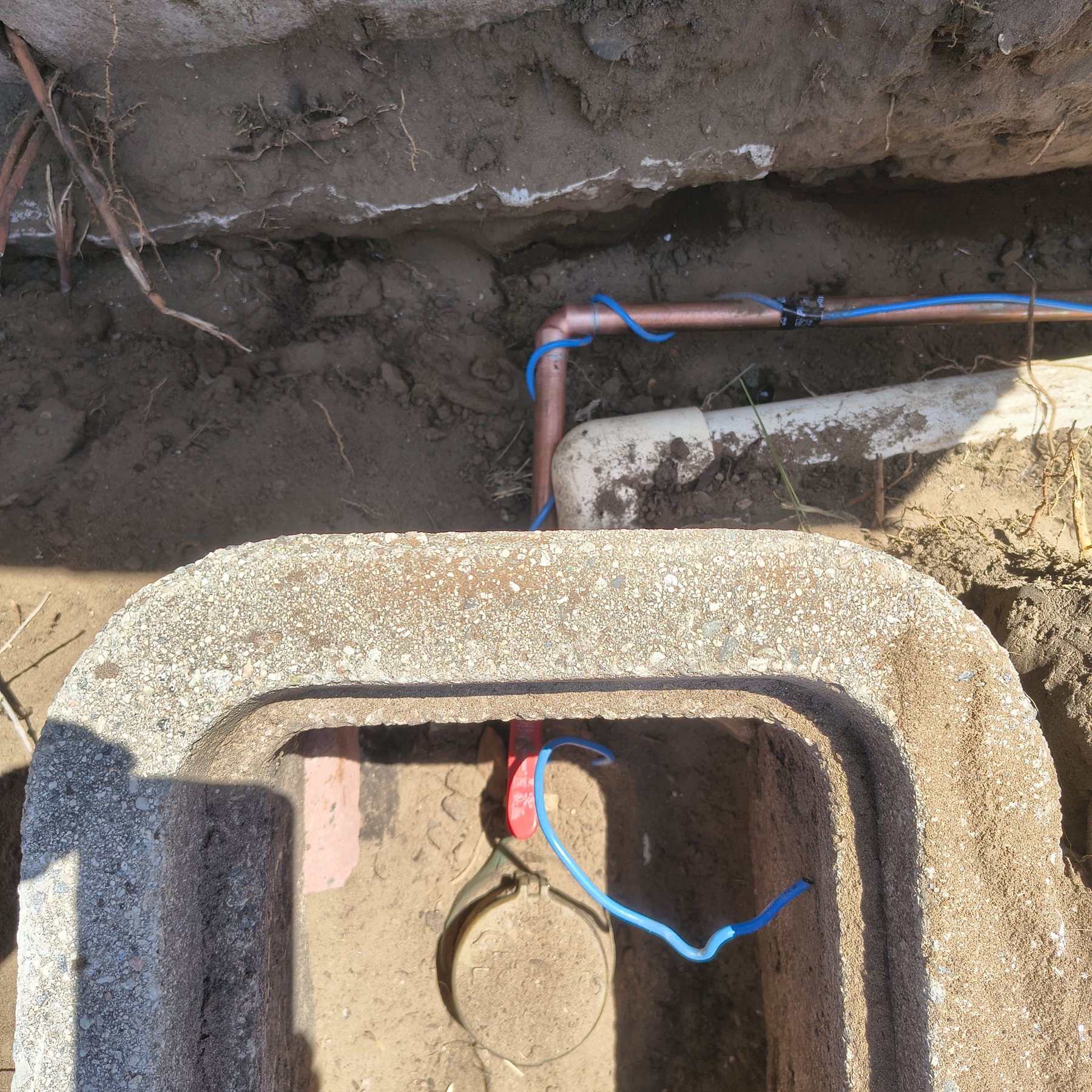 Water service piping exposed beside a meter box