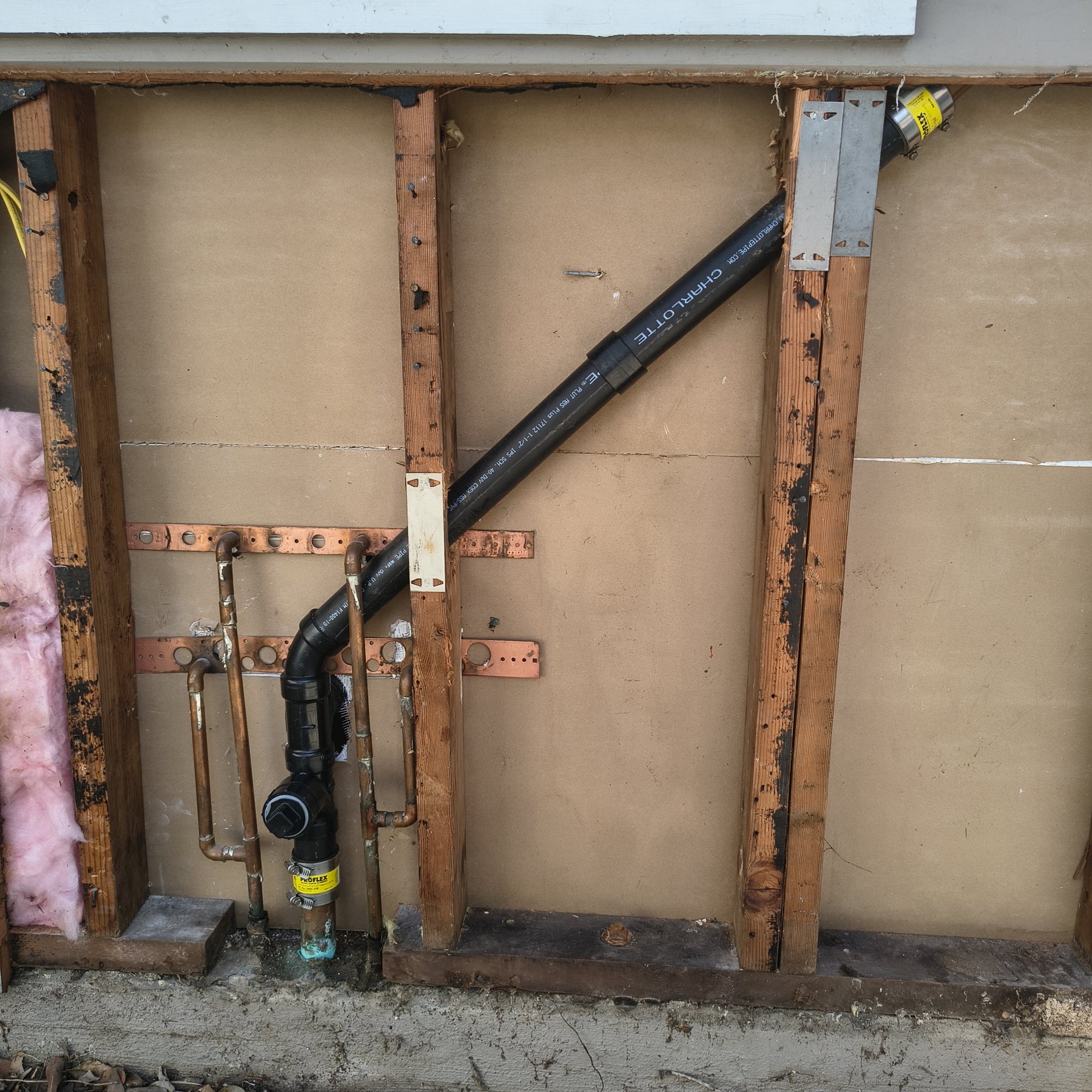 Real Water Fixers field photo of concealed supply and drain piping exposed inside a wall