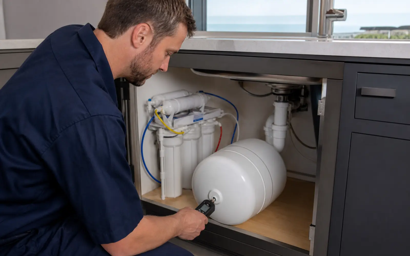 Technician checking air pressure in a reverse osmosis storage tank