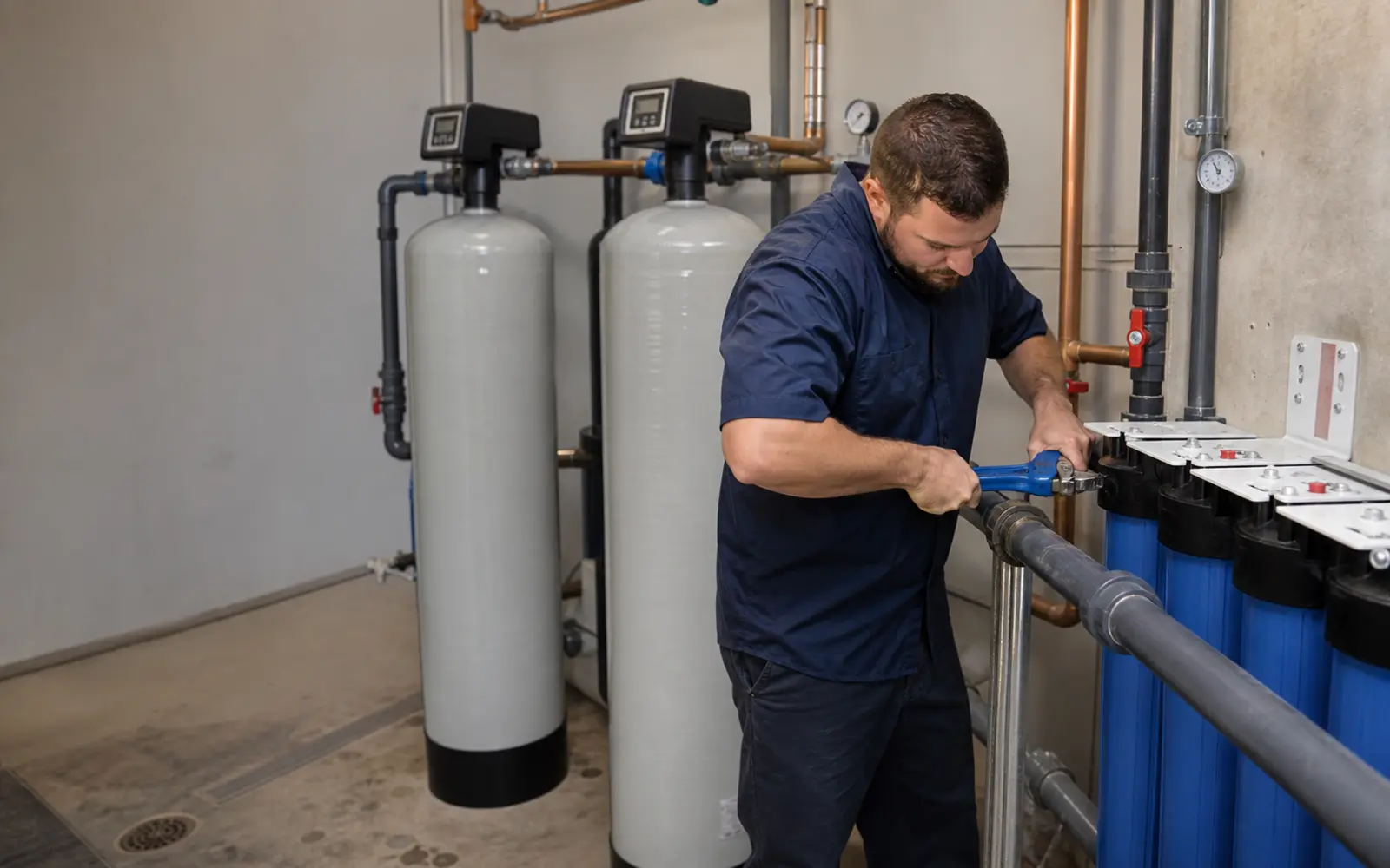 Commercial water treatment technician servicing filtration equipment on the California Central Coast